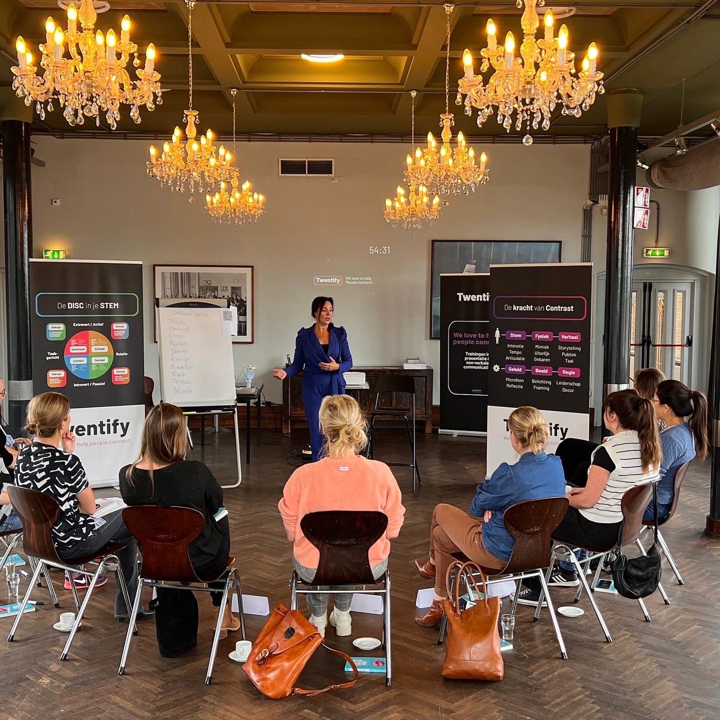 Debby Mureau geeft training in een zaal met kroonluchters