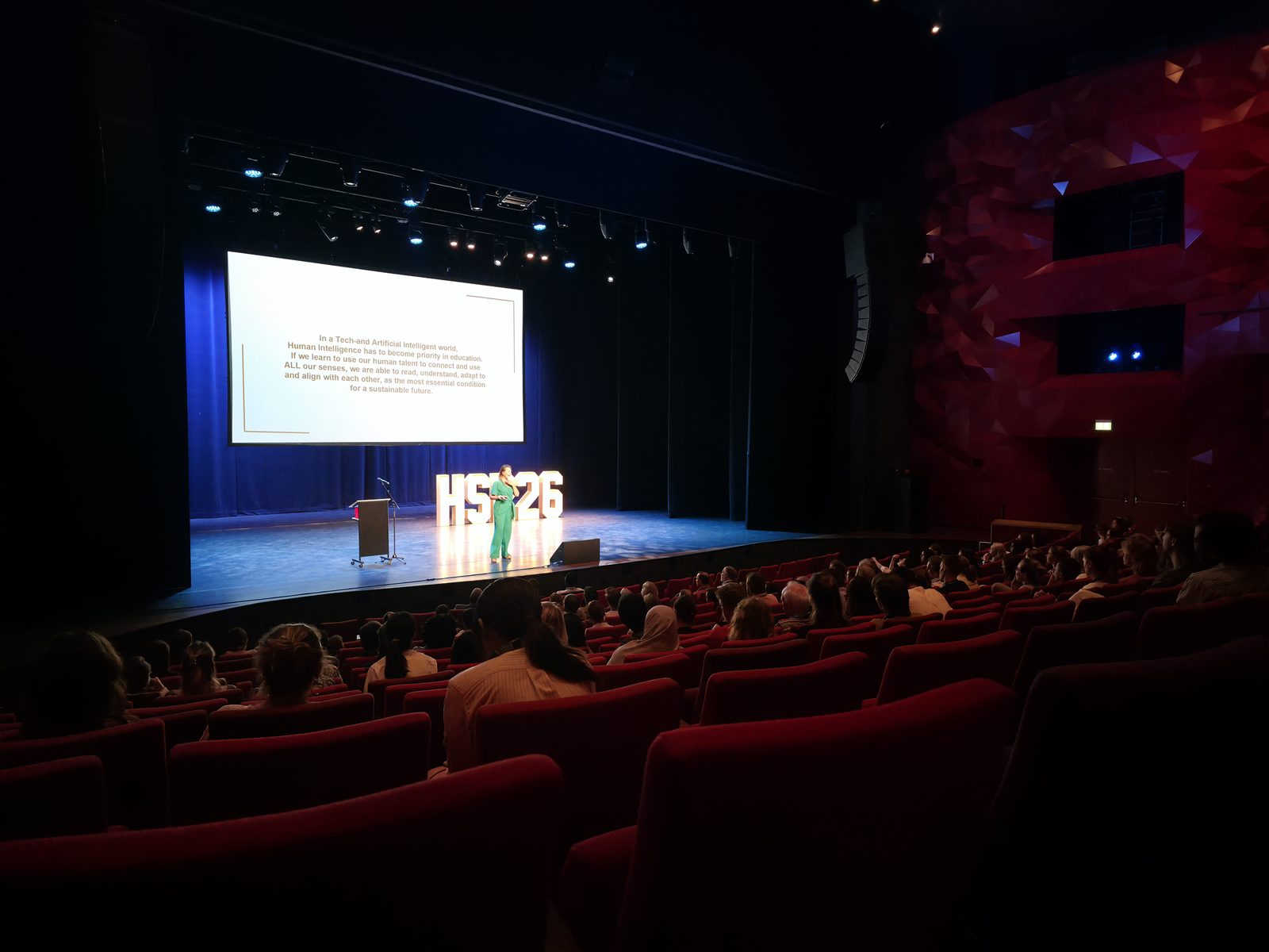 Debby Mureau op het podium van een volle theaterzaal